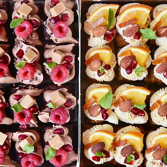 Cake bites boxed up and decorated with raspberries and oranges